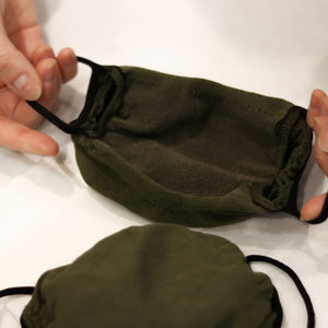 
                  
                    Woman handling olive green triple-layer mask
                  
                